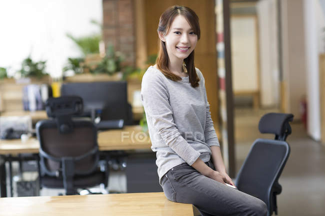 Chinês mulher sentada na mesa no escritório — Fotografia de Stock