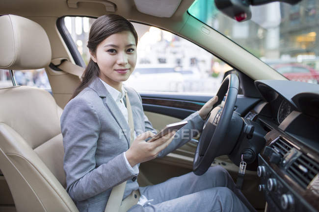 Chinese woman holding smartphone in car — Stock Photo