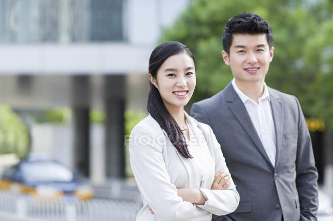 Chinese business people standing on street and looking in camera — Stock Photo