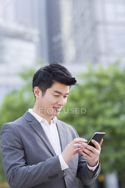 Китайский бизнесмен использует смартфон на улице — стоковое фото