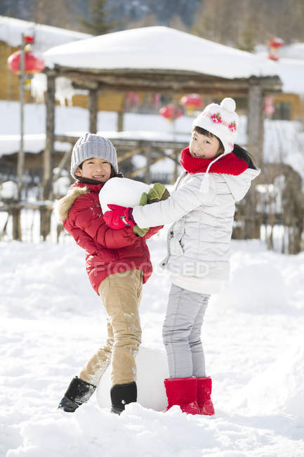 Hermanos chinos jugando con bola de nieve al aire libre - foto de stock