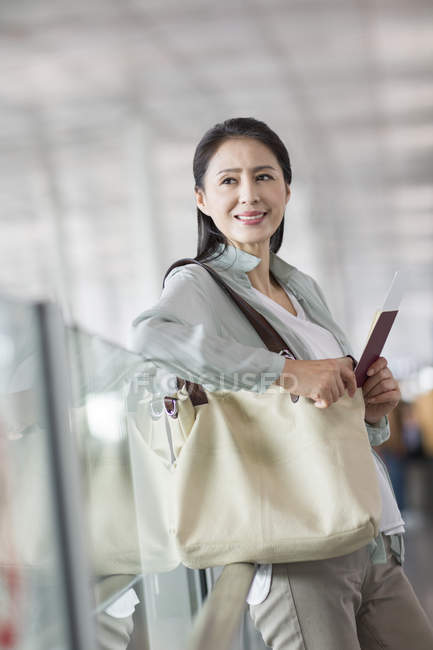 Femme chinoise mature attend à l'aéroport avec billet — Photo de stock