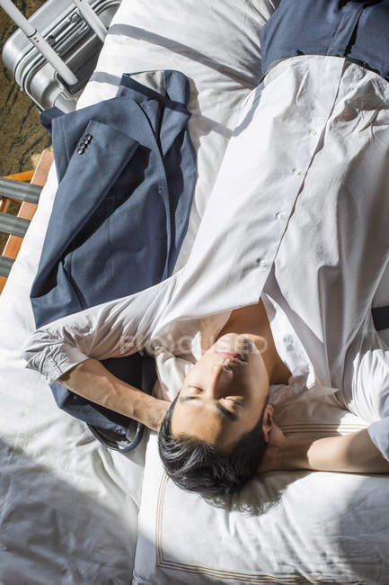 Empresário chinês descansando na cama no quarto de hotel — Fotografia de Stock
