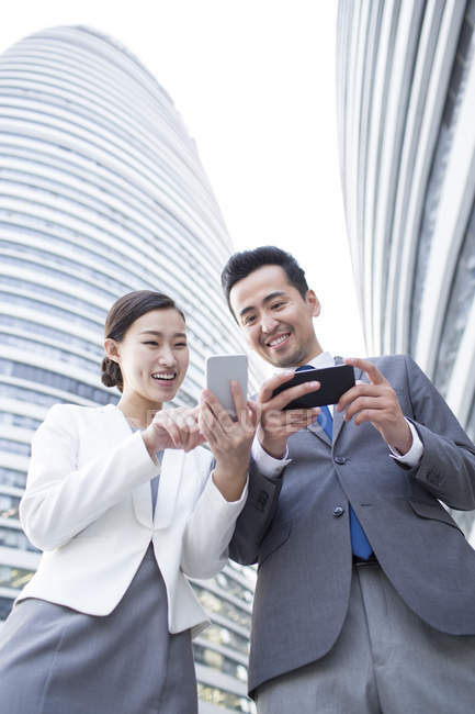 Chinese business people using smartphones in city — Stock Photo
