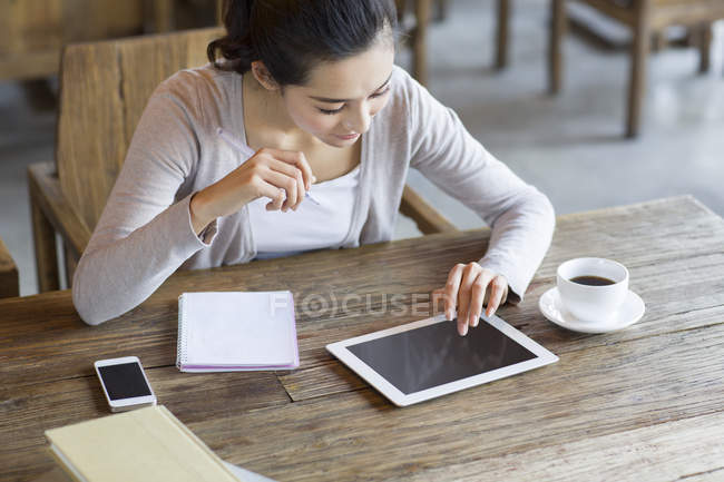 Estudiante chino estudiando en cafetería con tableta digital - foto de stock