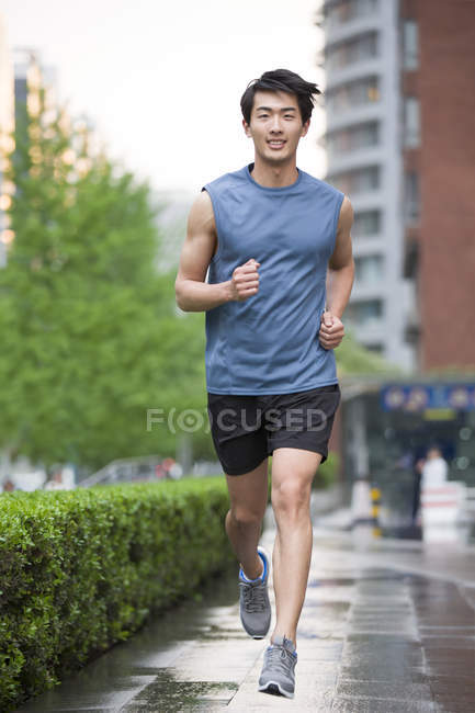 Chino hombre corriendo en la calle - foto de stock