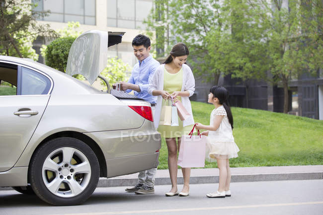 Chinese couple taking shopping bags from car trunk — Stock Photo