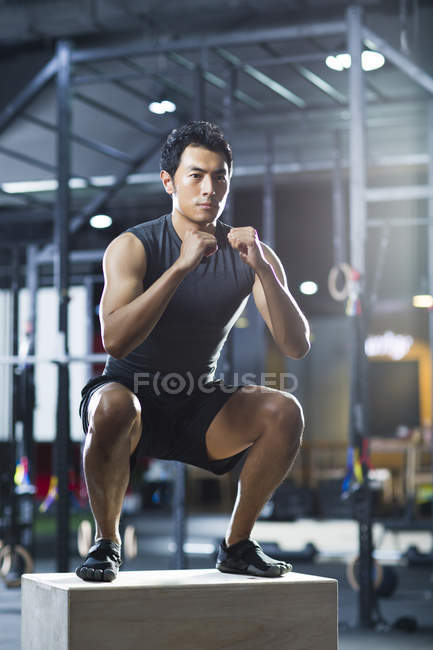 Chinese man doing box jump in crossfit gym — Stock Photo