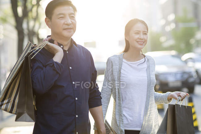 Reifes chinesisches Paar mit Einkaufstüten in der Stadt — Stockfoto
