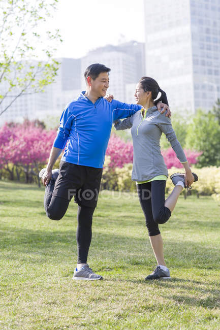 Mature chinese couple stretching in park — Stock Photo