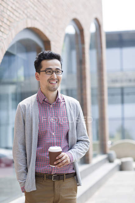 Chinese man holding cup of coffee — Stock Photo