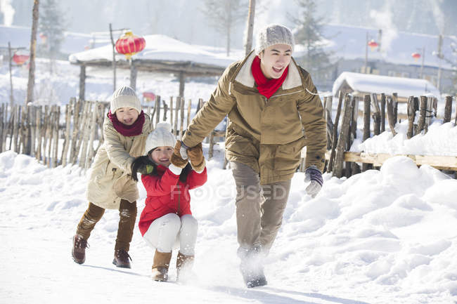 Китайский отец играет с детьми на открытом воздухе зимой — стоковое фото