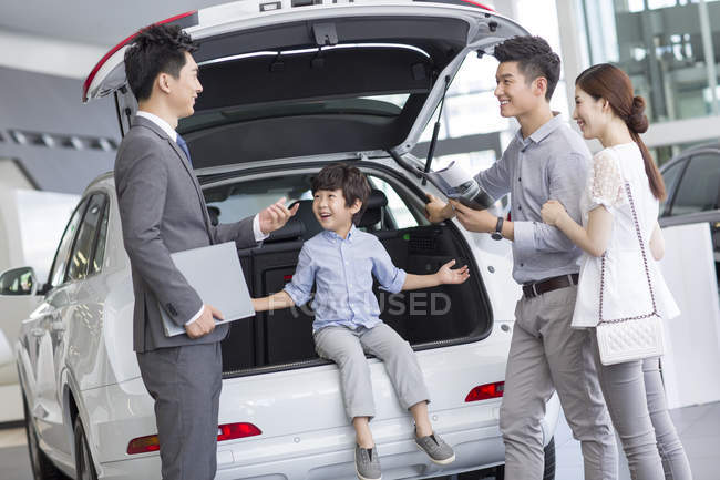 Китайская семья с сыном выбирает автомобиль с дилером — стоковое фото
