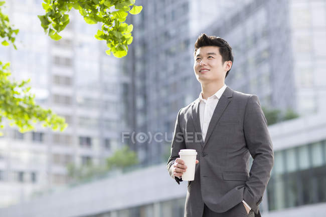 Homme d'affaires chinois debout avec tasse de café — Photo de stock