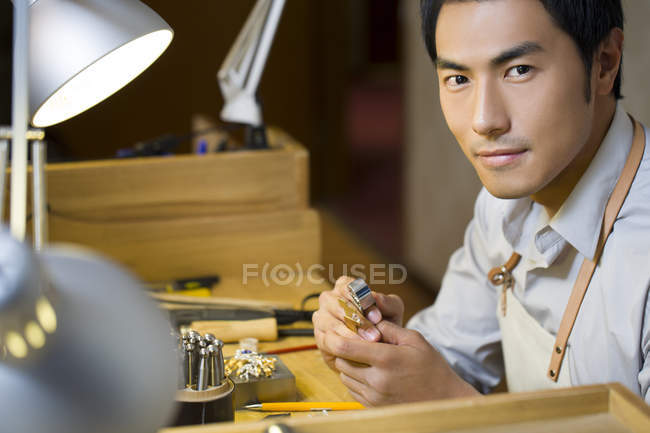 Joyero masculino chino trabajando en estudio - foto de stock