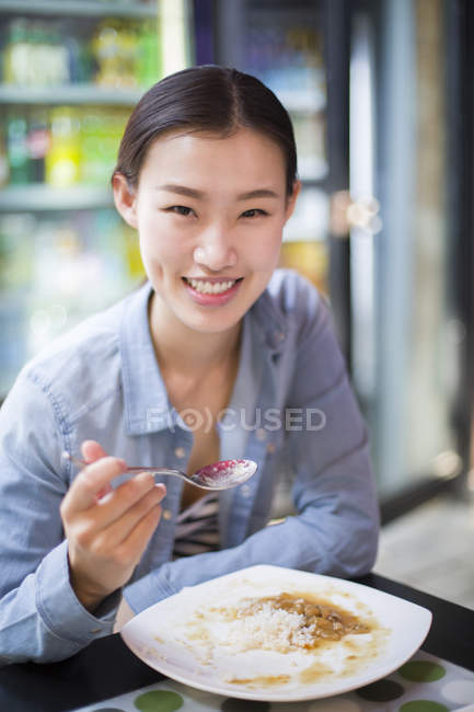 Chinese woman eating rice with spoon — Stock Photo