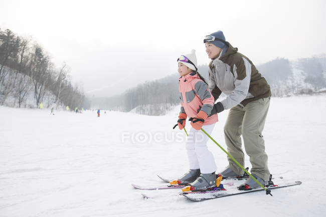 Pai chinês ensinando filha esquiar na encosta — Fotografia de Stock