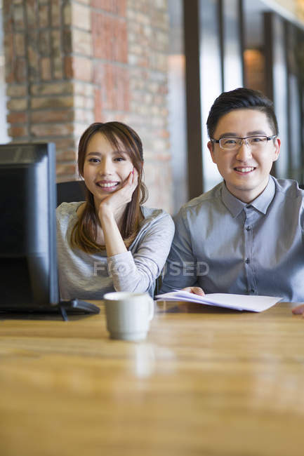 Chinesische Kollegen posieren am Schreibtisch im Büro — Stockfoto