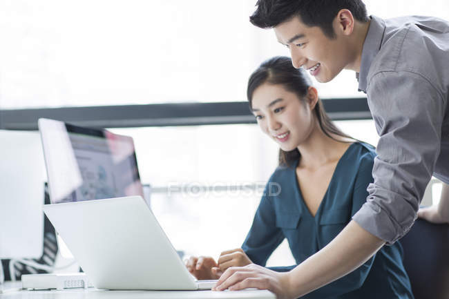 Chinese business co-workers using laptop in office — Stock Photo