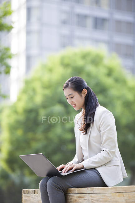 Femme d'affaires chinoise travaillant avec un ordinateur portable dans la rue — Photo de stock