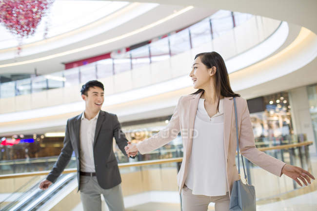 Chinese couple holding hands in shopping mall — Stock Photo