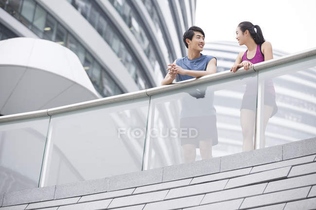 Chinese couple of joggers taking break and talking — Stock Photo