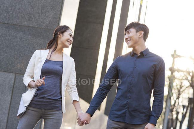 Chinese couple standing on street and holding hands — Stock Photo