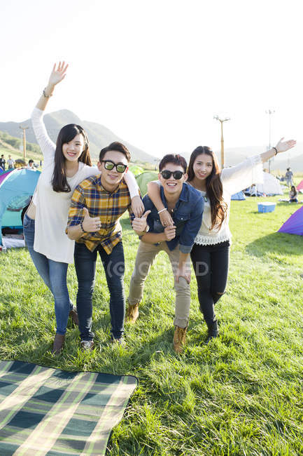 Chinese friends posing on grass at music festival — Stock Photo