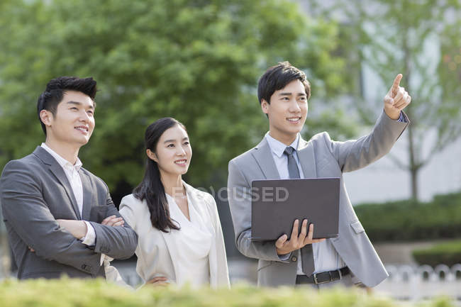 Les gens d'affaires chinois debout dans la rue avec ordinateur portable et pointant — Photo de stock