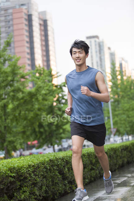 Chino hombre corriendo en la calle - foto de stock