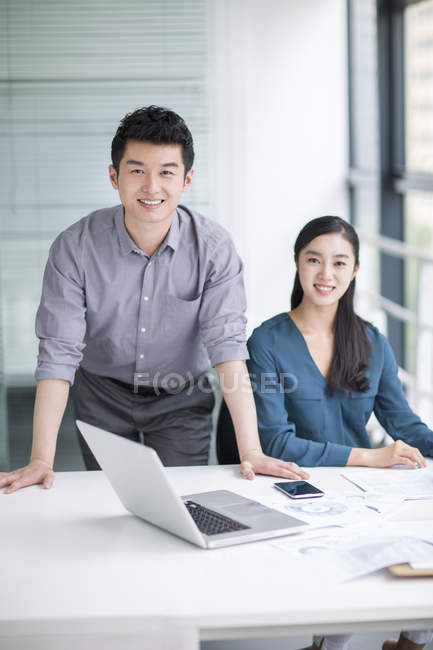 Chinese co-workers sitting in office and looking in camera — Stock Photo