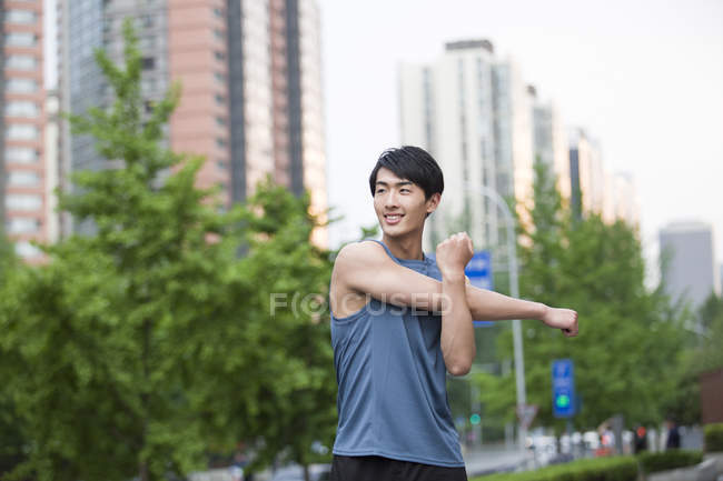 Chinese man stretching arms on street — Stock Photo
