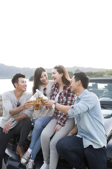 Amis chinois assis sur la voiture avec de la bière — Photo de stock