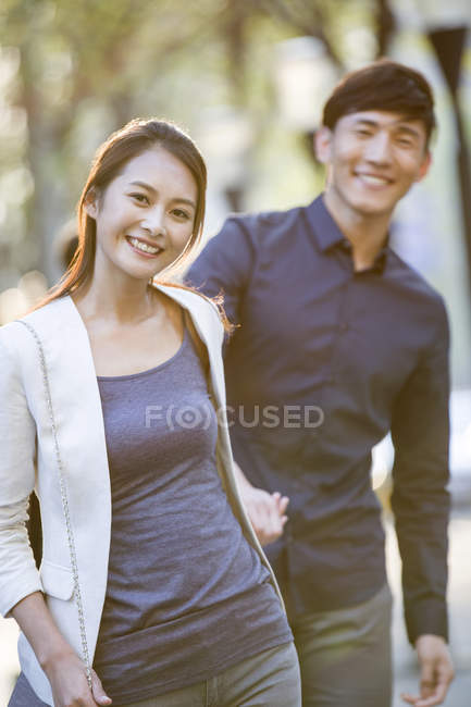 Chinesisches Paar hält Händchen, während es auf Bürgersteig geht — Stockfoto