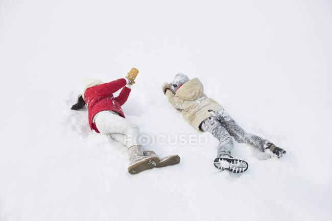 Kinder spielen und legen sich auf Schnee — Stockfoto