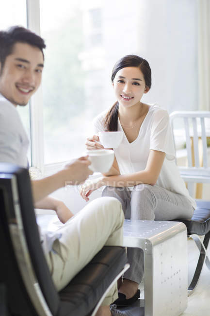 Couple chinois assis avec des tasses de café dans le café — Photo de stock