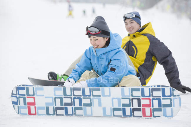 Casal chinês vestindo snowboards na neve — Fotografia de Stock