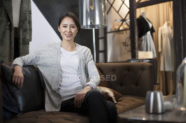 Propriétaire chinois de magasin de vêtements assis sur le canapé — Photo de stock