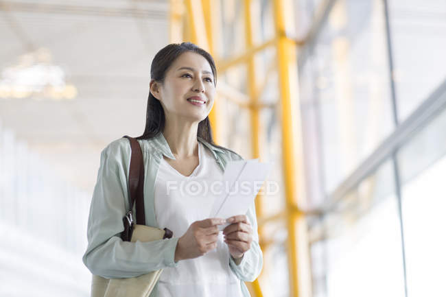 Femme chinoise mature attend à l'aéroport avec billet — Photo de stock
