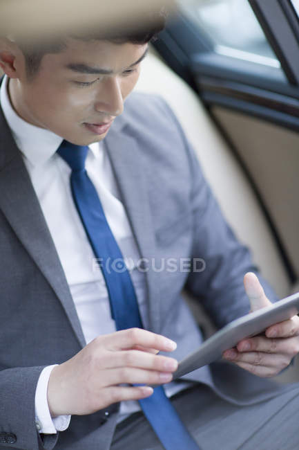 Chinesischer Geschäftsmann nutzt digitales Tablet im Auto — Stockfoto