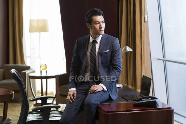 Chinesischer Geschäftsmann sitzt auf Schreibtisch im Home Office — Stockfoto