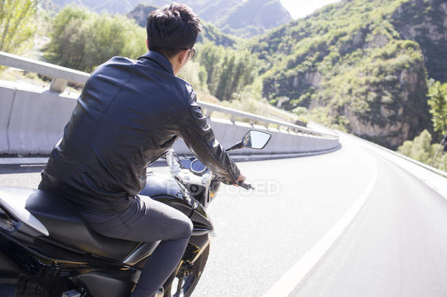 Chinese man riding motorcycle on highway — Stock Photo