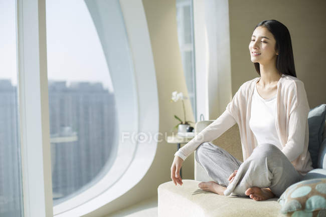 Chinesin meditiert mit geschlossenen Augen auf Sofa — Stockfoto