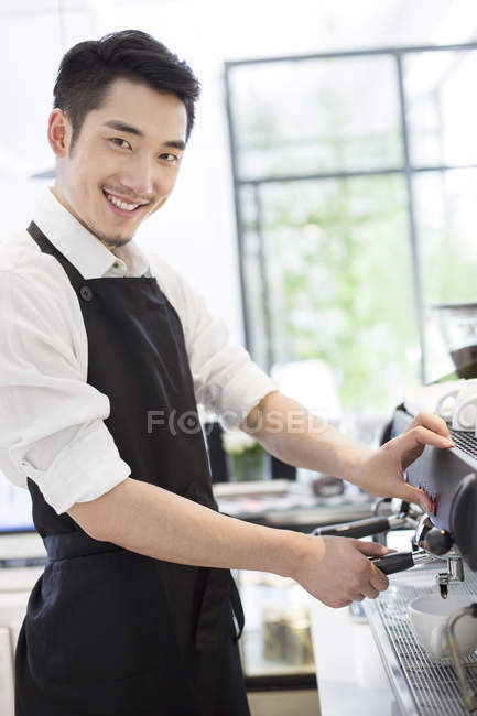 Barista standing at coffee maker and looking in camera — Stock Photo