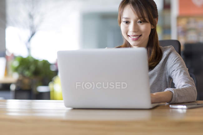 Mujer china usando portátil en la oficina - foto de stock
