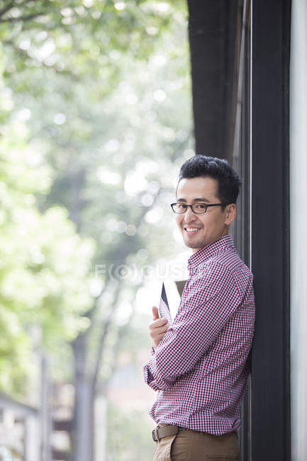 Homme chinois adulte moyen tenant tablette numérique et souriant — Photo de stock