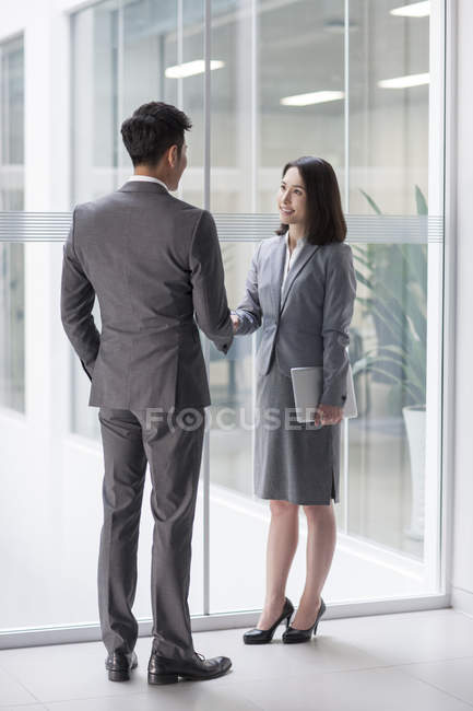 Chinese business people shaking hands in office building — Stock Photo