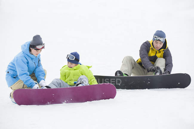 Pais chineses vestindo equipamento de snowboard no filho — Fotografia de Stock