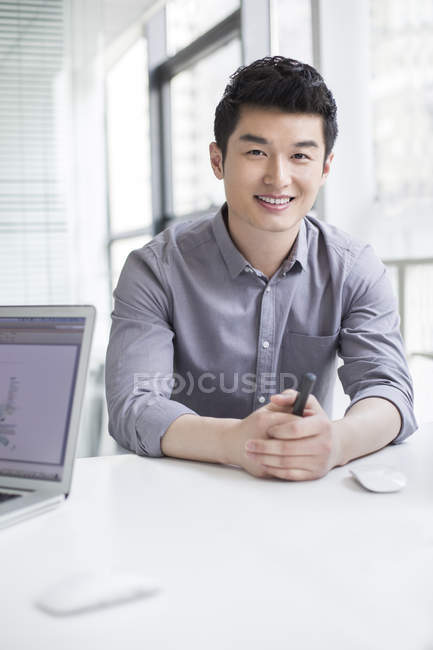 Empresário chinês sentado à mesa com as mãos apertadas — Fotografia de Stock