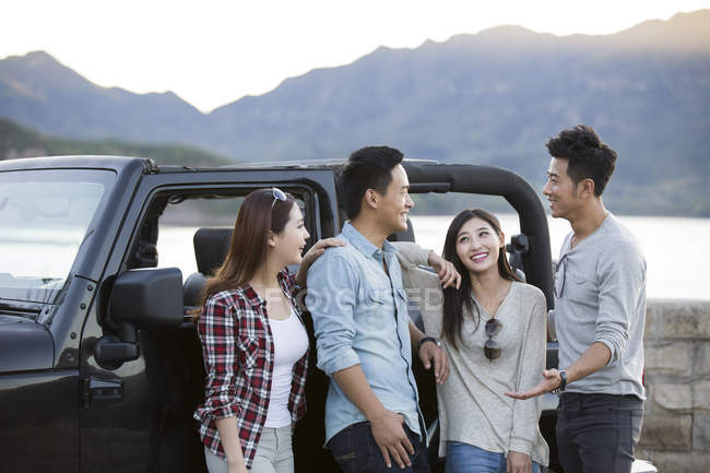 Китайские друзья общаются перед машиной в пригороде — стоковое фото